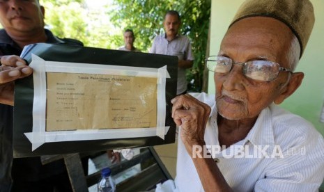 Nyak Sandang (kanan) memperlihatkan bukti obligasi pengumpulan uang untuk membeli pesawat pertama Indonesia di Desa Lhuet, Jaya, Aceh Jaya, Aceh, Rabu (14/3).