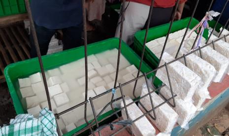 Nyoto Prawiro sedang membunkus tahu pesanan pembeli di lapaknya, PD Pasar Minggu, Jakarta Selatan, Ahad (3/1) sore. Nyoto adalah satu-satunya pedagang tahu dan tempe di PD Pasar Minggu pada hari ini. Sebab, sudah empat hari pengrajin tahu dan tempe mogok produksi lantaran harga kedelai naik hingga 35 persen