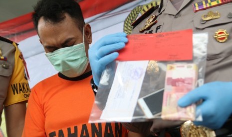 Oknum wartawan surat kabar tertunduk saat polisi memperlihatkan barang bukti kasus pemerasan. (Ilustrasi)