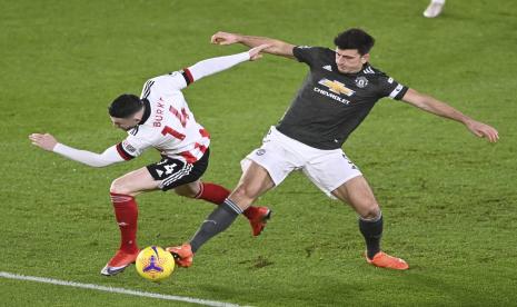 Oliver Burke dari Sheffield United (kiri) dihadang kapten Manchester United Harry Maguire dalam pertandingan sepak bola Liga Utama Inggris antara Sheffield United dan Manchester United di stadion Bramall Lane di Sheffield, Inggris, Jumat (18/12) dini hari WIB.