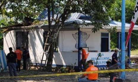 OM POSO. Sejumlah anggota kepolisian memeriksa tempat terjadinya ledkan bom di sebuah Pos Lalu Lintas di Kabupaten Poso, Sulawesi Tengah, Senin (22/10)