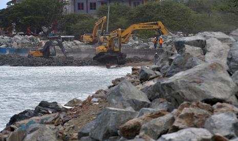 Operator alat berat menata tumpukan batu pada proyek pembangunan tanggul laut Teluk Palu di Palu, Sulawesi Tengah, Ahad (5/4/2020). Sejumlah proyek rehabilitasi dan rekonstruksi pasca bencana gempa, tsunami dan likuefaksi di daerah tersebut diupayakan tetap berjalan di tengah mewabahnya COVID-19