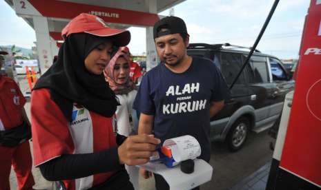 Operator membantu pengendara menggunakan kartu transaksi non tunai, untuk pembelian Bahan Bakar Minyak (BBM) di SPBU Pisang, Padang, Sumatera Barat, Rabu (19/9).