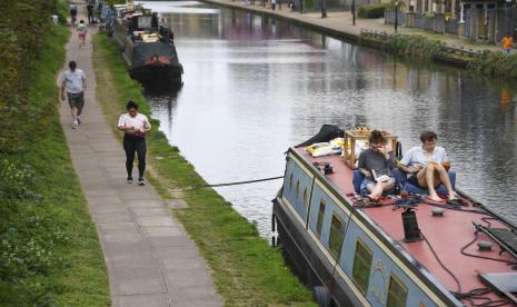 Orang berjalan di Regent Canal, London, Inggris, Sabtu (11/4). Sky News melaporkan kematian akibat virus corona di Inggris mencapai 9.875 orang. Inggris jumlah kematian dalam satu hari pada Sabtu (11/4), yaitu 917 orang, termasuk anak usia 11 tahun.