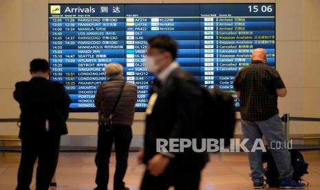  Orang-orang berdiri di depan papan informasi kedatangan di Bandara Internasional Haneda di Tokyo, Jepang, Senin (29/11).  Menanggapi munculnya varian baru Omicron dari Sars-CoV-2, Perdana Menteri Jepang Fumio Kishida memutuskan untuk melarang masuknya orang asing baru dari 30 November.