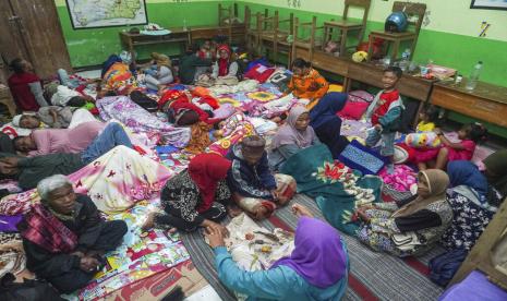  Orang-orang beristirahat di sekolah yang berubah menjadi tempat penampungan sementara bagi mereka yang dievakuasi dari rumah mereka setelah letusan Gunung Semeru, di Lumajang, Jawa Timur, Ahad, 4 Desember 2022. Gunung berapi tertinggi di Indonesia di pulau terpadatnya mengeluarkan gas yang membakar awan dan sungai lava Minggu dalam letusan terbarunya. 