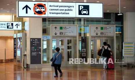  Orang-orang berjalan di bawah tanda yang mengatakan bahwa penumpang yang baru tiba tidak dapat menggunakan transportasi umum di Bandara Internasional Haneda di Tokyo, Jepang, Senin (29/11). Menanggapi munculnya varian baru Omicron Sars-CoV-2, Perdana Menteri Jepang Fumio Kishida memutuskan untuk melarang masuknya orang asing baru mulai 30 November. Indonesia juga memperketat aturan masuk bagi pelaku perjalanan internasional seiring peringatan adanya varian baru Omicron.