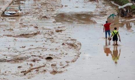 Orang-orang berjalan di jalan yang tertutup lumpur akibat banjir di Kota Picanya, Provinsi Valencia, Spanyol, 31 Oktober 2024.