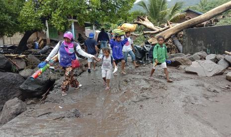 Orang-orang berjalan di tengah puing-puing di sebuah desa yang terkena banjir di Ile Ape, di Pulau Lembata, provinsi Nusa Tenggara Timur, Indonesia, Minggu, 4 April 2021 foto. Berbagai bencana yang disebabkan oleh hujan lebat di timur Indonesia telah menyebabkan puluhan orang tewas atau hilang sementara ribuan orang mengungsi, kata badan bantuan bencana negara itu, Senin.