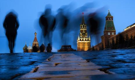 Orang-orang berjalan melalui Red Square setelah matahari terbenam di Moskow, Rusia, pada 3 Maret 2019, dengan latar belakang St. Basil di kiri, dan Menara Spasskaya, kedua di kanan.