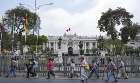 Orang-orang berjalan melewati gedung Kongres selama kunjungan delegasi OAS di Lima, Peru, Senin, 21 November 2022. Presiden Peru Pedro Castillo telah menerima pengunduran diri perdana menteri negara tersebut dan akan kembali melakukan perombakan kabinet, sebagaimana dikatakan pada Kamis (24/11/2022) waktu setempat.