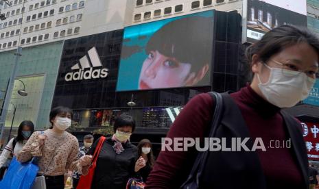  Orang-orang berjalan melewati toko pakaian olahraga Adidas di Hong Kong, Sabtu (27/3). 