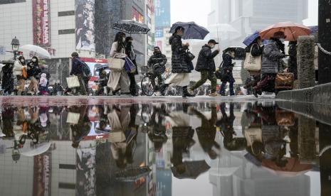 Orang-orang berjalan melintasi persimpangan Shibuya yang terkenal saat salju turun Kamis, 6 Januari 2022, di Tokyo.   Pemerintah Jepang akan menempatkan Tokyo dan selusin daerah lainnya di bawah pembatasan baru untuk Covid-19 mulai Jumat (21/1/2022).