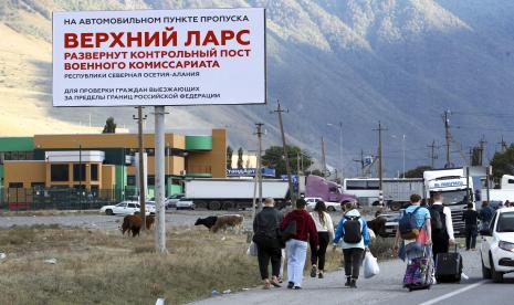 Orang-orang berjalan menuju penyeberangan perbatasan di Verkhny Lars antara Georgia, bawah, dan Rusia meninggalkan Chmi, Ossetia Utara-Republik Alania, Rusia, Rabu, 28 September 2022. Antrean panjang kendaraan telah terbentuk di perbatasan antara wilayah Ossetia Utara Rusia dan Georgia setelah Moskow mengumumkan mobilisasi militer parsial. Sehari setelah Presiden Vladimir Putin memerintahkan mobilisasi parsial untuk memperkuat pasukannya di Ukraina, banyak orang Rusia meninggalkan rumah mereka. 