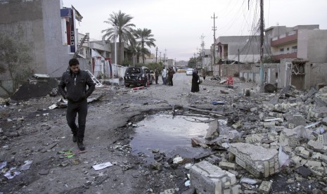 Orang-orang berkumpul dengan ceruk bekas bom mobil di New Baghdad, Irak, Selasa, 12 Januari 2016.