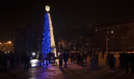 Orang-orang berkumpul di sekitar pohon Natal yang dihiasi warna bendera nasional Ukraina di alun-alun Sophia di Kyiv, Ukraina, Jumat, 23 Desember 2022.