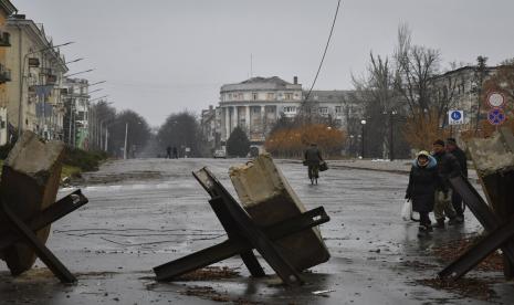 Orang-orang melewati barikade anti-tank di Bakhmut, tempat pertempuran terberat dengan pasukan Rusia, di wilayah Donetsk, Ukraina, Jumat, 16 Desember 2022.