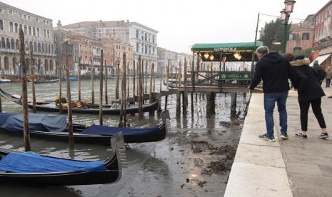 Orang-orang melihat gondola berlabuh di sepanjang kanal saat air surut di Venesia, Italia, Selasa, 21 Februari 2023. Beberapa kanal sekunder Venesia praktis mengering akhir-akhir ini karena gelombang pasang surut yang berkepanjangan terkait dengan sistem cuaca bertekanan tinggi yang berkepanjangan. 