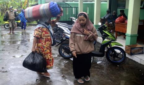  Orang-orang membawa barang-barang mereka saat tiba di sebuah sekolah yang menjadi tempat penampungan sementara bagi mereka yang terkena dampak letusan Gunung Semeru, di Lumajang, Jawa Timur, Ahad, 4 Desember 2022. Gunung berapi tertinggi di Indonesia di pulau terpadatnya dirilis awan gas yang membakar dan sungai lava hari Ahad dalam letusan terbarunya. 