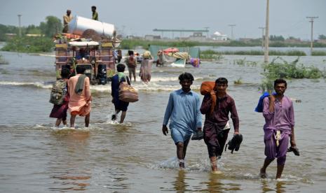 Warga mengarungi daerah banjir Sohbatpur, sebuah distrik di provinsi Baluchistan barat daya Pakistan, Senin, 29 Agustus 2022. Bantuan internasional mencapai Pakistan pada hari Senin, ketika militer dan sukarelawan dengan putus asa berusaha untuk mengevakuasi ribuan orang yang terdampar oleh banjir yang meluas yang didorong oleh monster monsun yang telah merenggut lebih dari 1.000 nyawa musim panas ini.