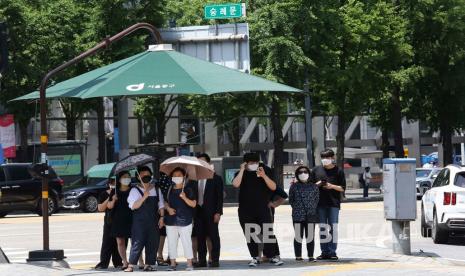  Orang-orang mengenakan masker menunggu untuk menyeberang jalan di Seoul, Korea Selatan, Kamis (11/6). Beberapa minggu yang lalu Korea Selatan merayakan keberhasilannya melawan coronavirus dengan melonggarkan jaga jarak, membuka kembali sekolah dan mempromosikan metode berbasis teknologi untuk memerangi penyebaran virus. Namun, meningkatnya jumlah kasus baru di Seoul, di mana sekitar setengah dari 51 juta penduduk negara itu tinggal, mengancam kisah sukses negara itu, dan mendorong pihak berwenang kesehatan untuk memperingatkan bahwa tindakan drastis harus diambil sekarang untuk menghentikan kemungkinan terjadinya gelombang kedua wabah virus corona. 