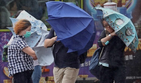 Orang-orang menyeberang jalan saat hujan deras dan angin kencang yang dibawa oleh badai tropis Bailu, di Taipei, Taiwan.