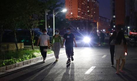 Orang-orang yang memakai masker berjalan di sepanjang jalan di dalam komunitas perumahan di Shanghai, Cina, Senin, 11 April 2022.