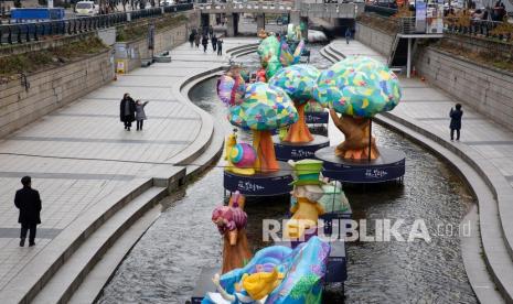  Orang-orang yang memakai masker berjalan di sepanjang sungai Cheonggyecheon di Seoul, Korea Selatan, Senin (29/11).  Korea Selatan (Korsel) akan menerapkan kembali aturan jarak sosial yang lebih ketat menyusul jumlah infeksi baru Covid-19 yang kian meningkat. 