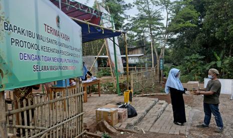 Orang tua santri memberikan paket untuk anak di pos pengumpulan paket kawasan Pondok Pesantren Darussalam, Kersamanah, Kabupaten Garut, Jawa Barat, Senin (9/11/2020). Selain menerapkan 3M, pondok pesantren tersebut juga memperketat protokol kesehatan seperti menyediakan pos paket bagi orang tua sehingga tidak diperbolehkan bertemu dengan anaknya dan menyediakan fasilitas telepon genggam untuk berkomunikasi dengan orang tua guna menghindari risiko penyebaran COVID-19 di lingkungan pesantren.