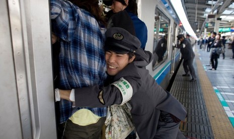 Oshiya sedang bekerja mendorong penumpang masuk ke kereta di Jepang.