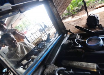 Paijo (56) pemangkas rambut di bawah jembatan layang Cawang, Jalan Dewi Sartika, Jakarta Timur, Ahad (18/12). (Republika/Aditya Pradana Putra)