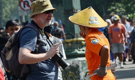  Pak Sariban berbincang dengan seorang wisatawan saat bertugas di jalan Ir H. Djuanda,Bandung,Ahad (31/3). (Republika/Edi yusuf)