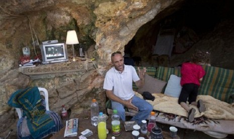 Palestinian Khaled Zir sits with his children inside a cave in the east Jerusalem neighborhood of Silwan, Tuesday, Aug. 27, 2013. Zir said the family moved into a cave after their home was demolished by Israeli authorities. 