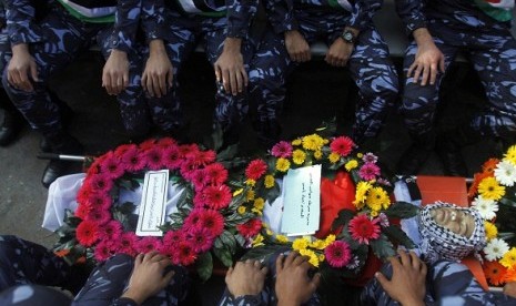 Palestinian policemen sit besides the body of their comrade Rushdi Tamimi (31 years), during his funeral procession in the West Bank city of Ramallah November 20, 2012. Residents said Tamimi died after he was shot in the stomach during a demonstration on S