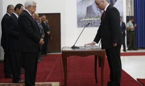 Palestinian Prime Minister Rami Hamdallah (right) stands in front of Palestinian President Mahmoud Abbas during a swearing-in ceremony of the unity government, in the West Bank city of Ramallah June 2, 2014.