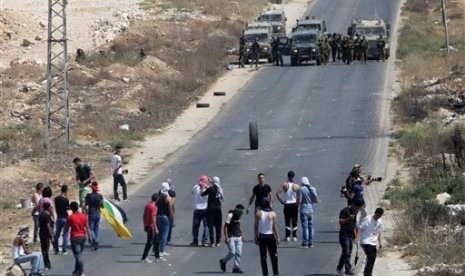 Palestinian protesters face Israeli soldiers, following a demonstration to support people in Gaza and Palestinian negotiators in Egypt, during clashes near the West Bank city of Nablus on Friday, Aug. 15, 2014. 