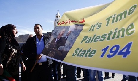 Palestinians hold a banner during a rally in the West Bank town of Bethlehem, supporting the resolution that would change the Palestinian Authority's United Nations observer status from 