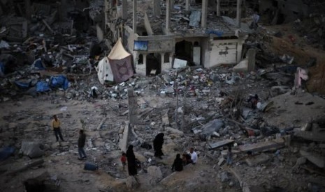 Palestinians sit atop the ruins of their house which witnesses said was destroyed during the Israeli offensive, in the east of Gaza City September 3, 2014.