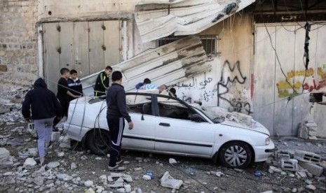 Palestinians stand next to a car damaged during the demolition of Abdel-Rahman Shaloudi's home in the East Jerusalem neighborhood of Silwan November 19, 2014.