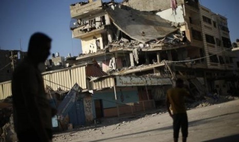 Palestinians stand next to a house which police said was targeted in an Israeli air strike in Gaza City July 17, 2014.