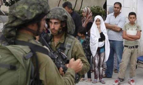 Palestinians stand outside their house as Israeli soldiers take part in an operation to locate three Israeli teens near the West Bank City of Hebron June 21, 2014.