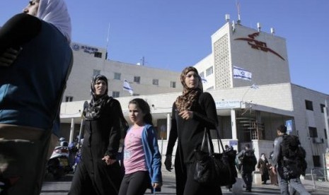 Palestinians walk past a post office building in East Jerusalem April 29, 2014. 