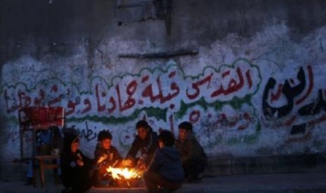 Palestinians warm themselves during a rainy day at Shati refugee camp in Gaza City March 14, 2014. 