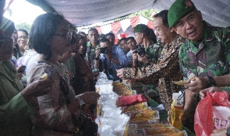 Pangdam XVI/Pattimura Mayjen TNI Meris Wiryadi (kanan) dan Direktur Sinar Mas Gandi Salistijanto (kedua kanan) melayani warga yang antri membeli minyak goreng saat bazar minyak goreng murah di halaman Kodam XVI/Pattimura, Ambon, Maluku, Minggu (20/7).