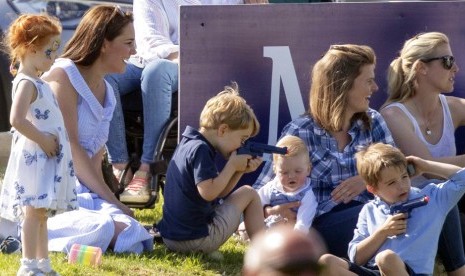 Pangeran George memegang mainan pistol-pistolan ditemani ibunya Kate Middleton, saat menyaksikan pertandingan polo Pangeran William.