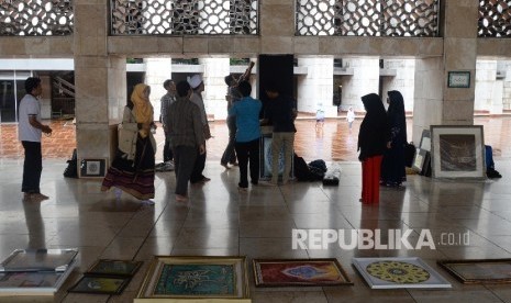 Panitia memasang kaligrafi untuk mempersiapkan pameran di Masjid Istiqlal, Jakarta, Ahad (19/2).