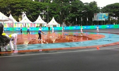 Panitia pelaksana berusaha mengeringkan lintasan sepatu roda di Saparua Sport Park, Bandung yang diguyur hujan menjelang final Individual Time Trial sepatu roda PON XIX, Kamis (22/9).