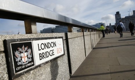 Para pejalan kaki melewati seorang polisi di London Bridge, London, Senin (5/6). Polisi menahan beberapa orang dan melakukan penyelidikan setelah rangkaian serangan diduga sebagai aksi terorisme menewaskan beberapa orang dan melukai lebih dari 40 lainnya di jantung kota London. 