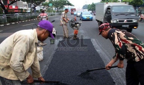 Para pekerja dari Dinas PU DKI Jakarta menambal jalan yang berlubang di Jalan Kramat Raya, Jakarta, Senin (17/6).    (Republika/ Yasin Habibi)