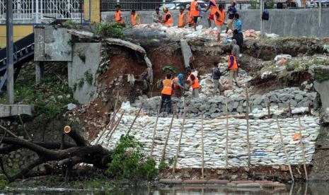 Para pekerja menata batu kali saat memperbaiki tanggul waduk Setia Budi, Jakarta Pusat, Ahad (26/1). (